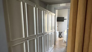A hallway with a large wardrobe, a flat-screen TV mounted on the wall, and a herringbone-patterned floor. - Loft33 (Barletta)