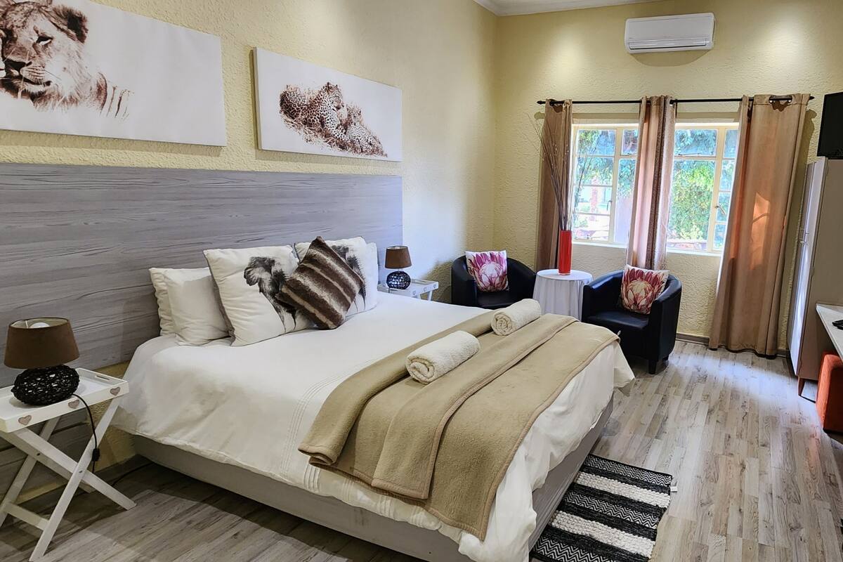 A hotel room with a bed, a desk, a chair, a TV, and artwork on the walls.