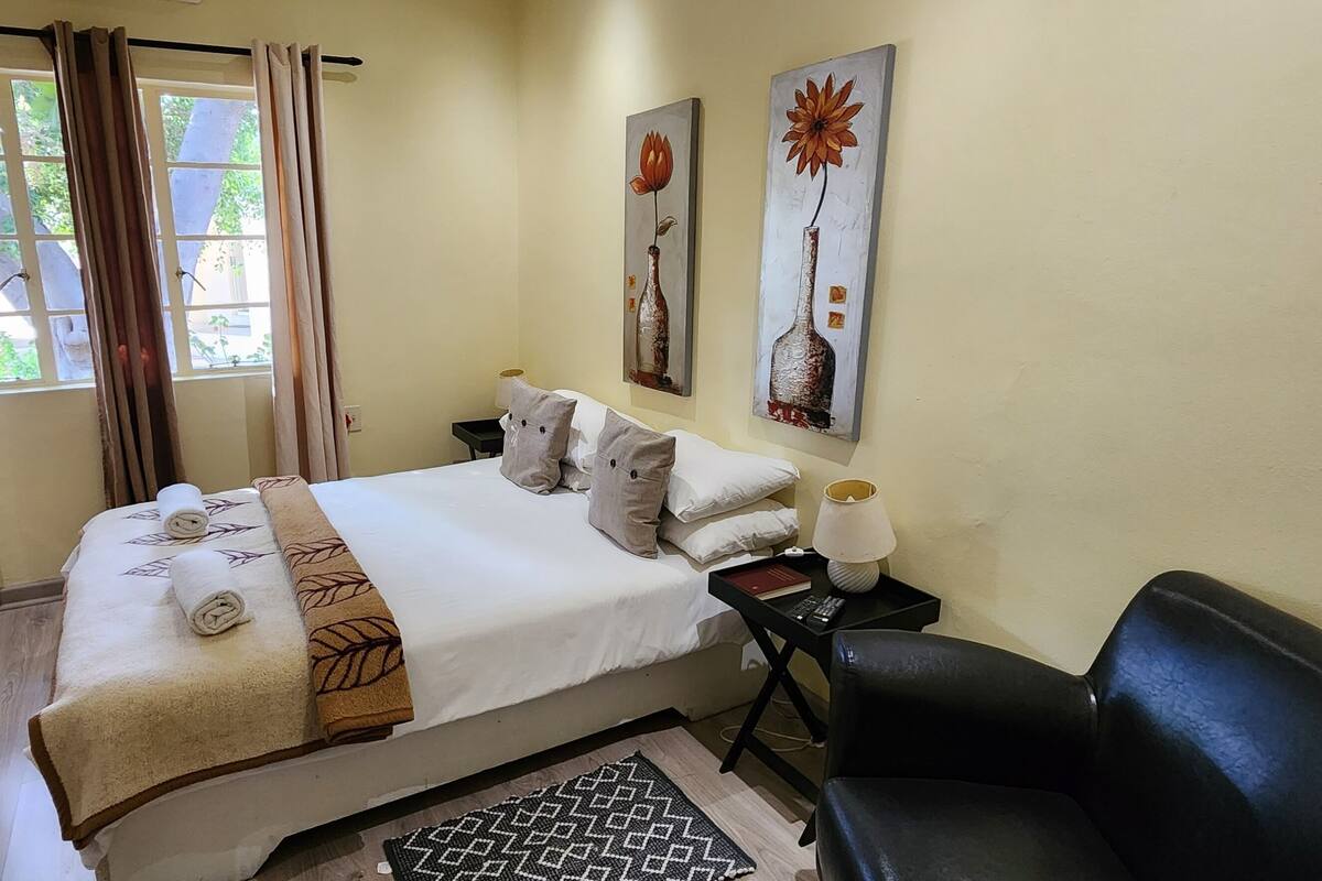 A neatly made bed with towels, a bedside table with a lamp, and two wall-mounted paintings.
