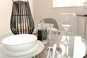 Uma mesa de jantar posta com pratos brancos, copos transparentes e talheres.