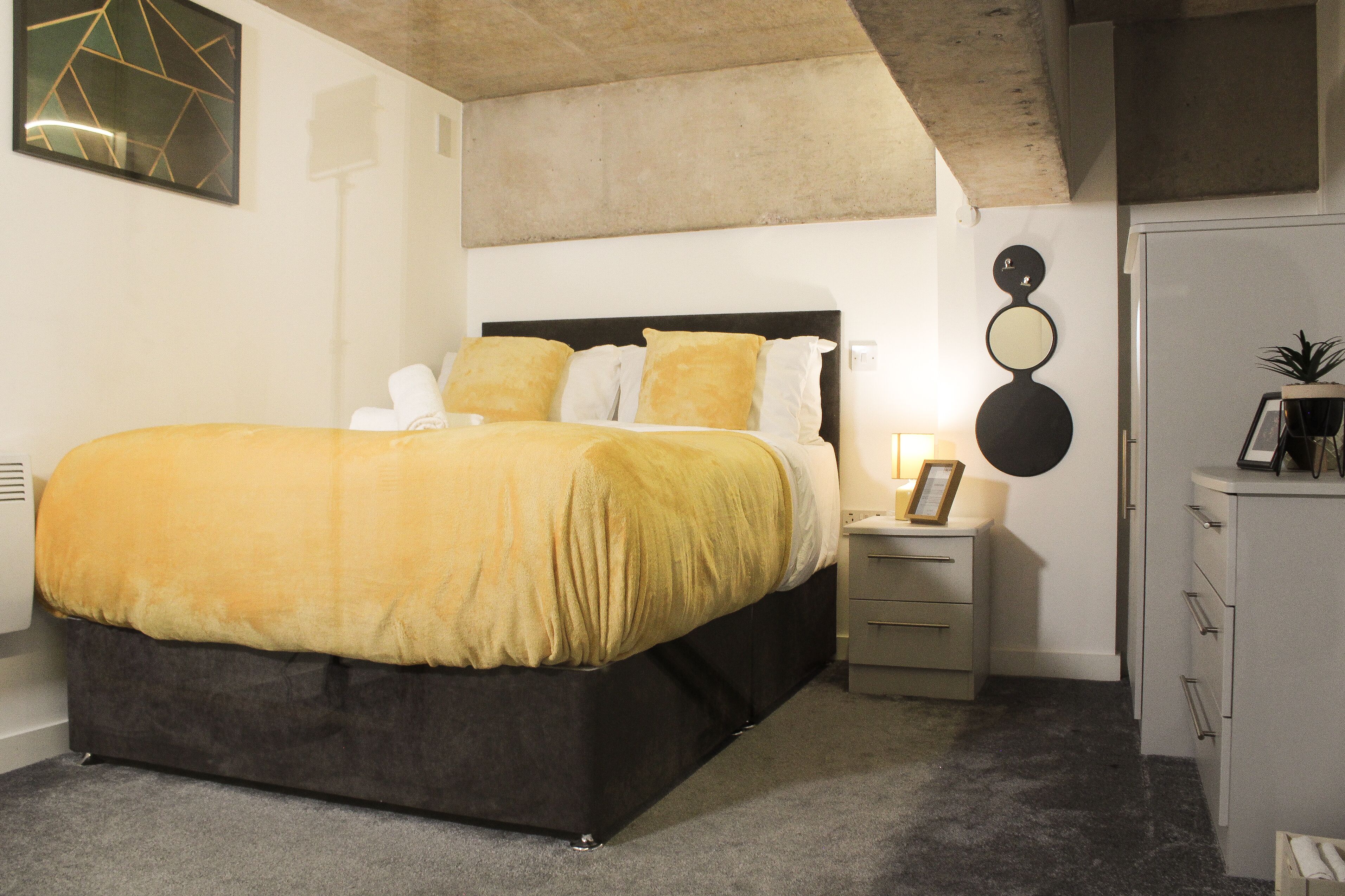 A modern bedroom with a large bed, bedside tables, and a wardrobe.