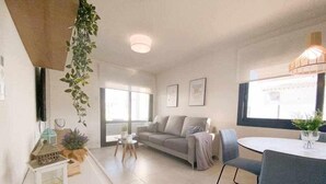 Ein modernes Wohnzimmer mit einer Couch, einem Esstisch mit Stühlen und einem großen Fenster, das für natürliches Licht sorgt.