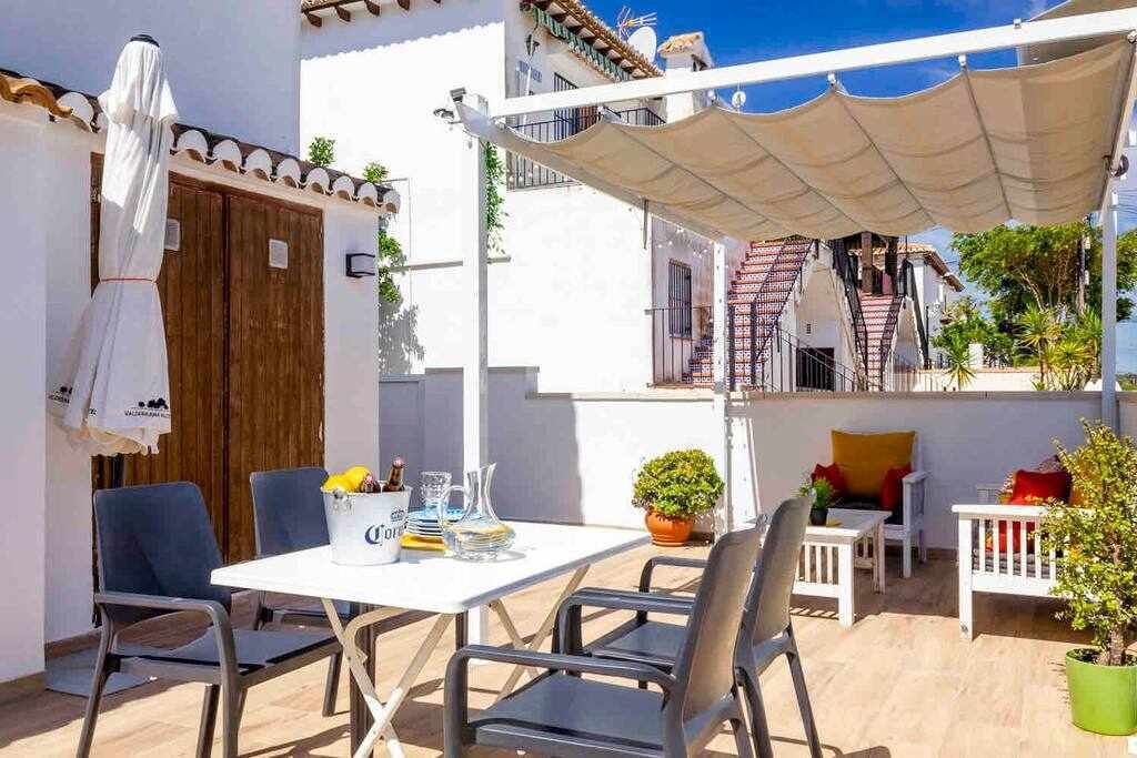 Une terrasse extérieure avec une table, des chaises et des plantes en pot.