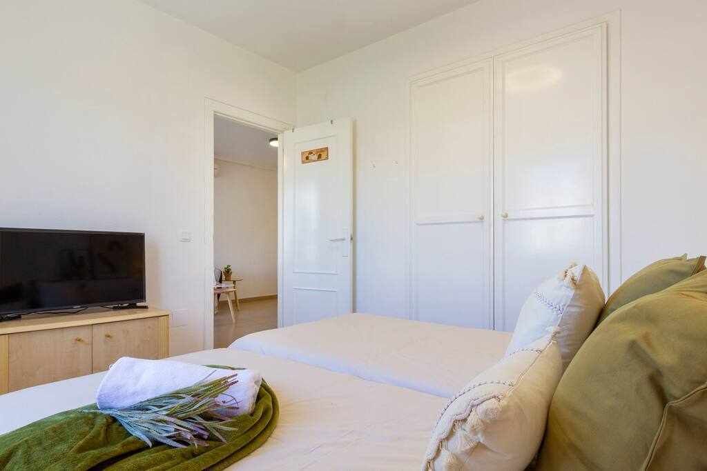 A bedroom with a bed, a television on a wooden cabinet, and a door leading to another room.