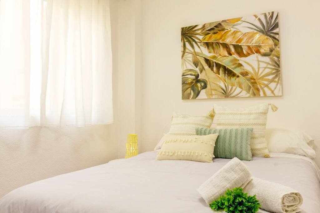A bedroom with a bed, pillows, a blanket, and a wall art piece.