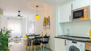 A compact living space with a dining area, a washing machine, and a microwave. - Pink port apartment (Torrevieja)