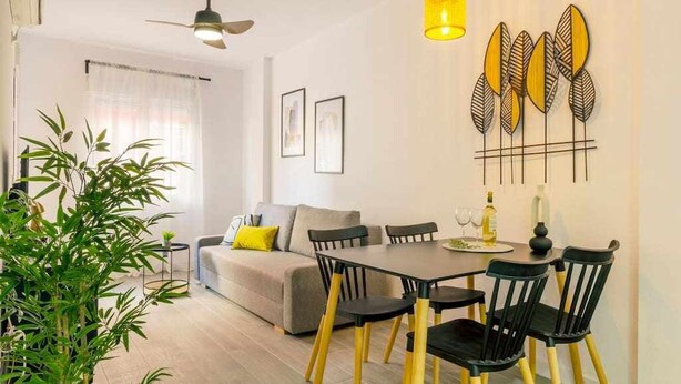 A modern living room with a sofa, dining table, chairs, and a ceiling fan. - Pink port apartment (Torrevieja)