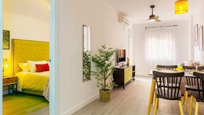 A room with a bed, a dining table with chairs, a television, and a plant. - Pink port apartment (Torrevieja)