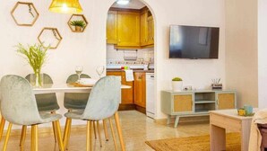 Una cocina moderna con armarios de madera, un televisor montado en la pared y un comedor con mesa y sillas.
