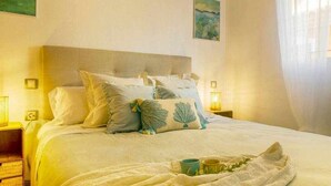 Una cama bien hecha con cabecera, dos lámparas de noche y una bandeja con tazas sobre la cama.