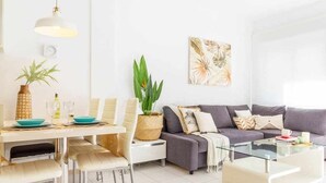 Ein modernes Wohnzimmer mit Essbereich, ausgestattet mit einer Couch, Couchtisch und einem Esstisch mit Stühlen.