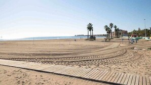 A beach with a wooden boardwalk, palm trees, and a clear sky. - Lovely Groundfloor with swimming pool (Torrevieja)