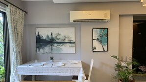 Un comedor con una mesa preparada para cuatro personas, un banco y una planta en maceta.