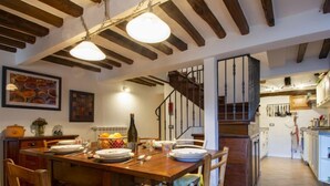 A dining area with a wooden table, chairs, and hanging pendant lights. A staircase leads to an upper level. - Vacation home Kenzo by Interhome (Bagni di Lucca)