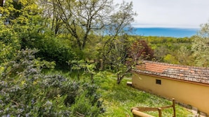Un bâtiment rustique, doté d’un toit en tuiles, entouré d’une végétation luxuriante et d’arbres.