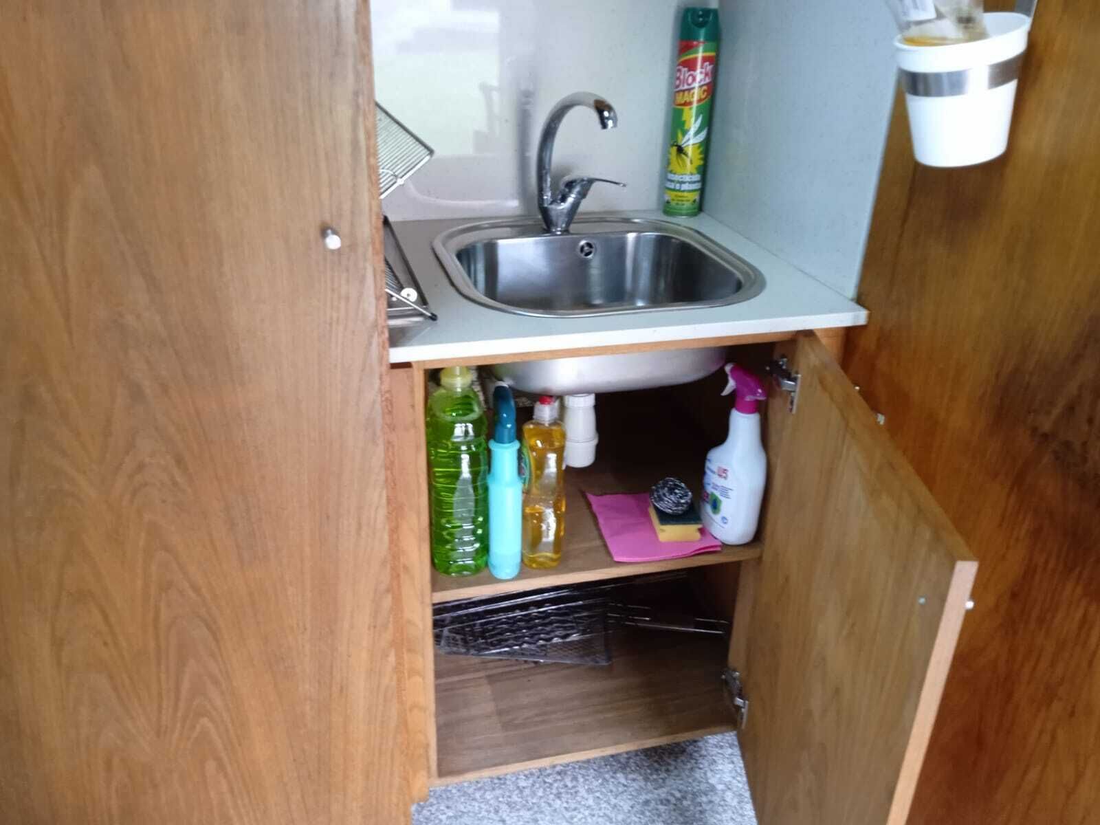 Une cuisine de taille réduite, équipée d’un évier, de placards de rangement et d’un plan de travail.