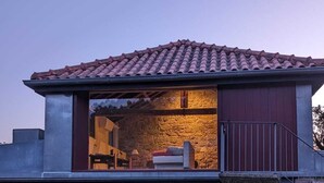 A modern house with a stone wall, a tiled roof, and a large garage door. - Villa em Arcos de Valdevez - Quinta com piscina privada , adequado para familias (Gondoriz - Arcos de Valdevez)