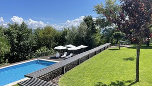 A swimming pool with a wooden deck and lounge chairs, surrounded by a well-maintained lawn and trees. - Villa em Arcos de Valdevez - Quinta com piscina privada , adequado para familias (Gondoriz - Arcos de Valdevez)