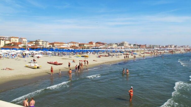 A beach with sun loungers and umbrellas, a boat, and people in the water. - Villa Clara by Interhome (Lido di Camaiore)