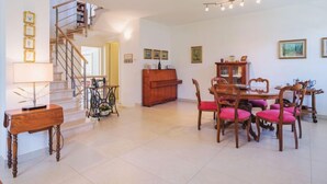 A spacious living area with a staircase, a dining table with chairs, and a wooden cabinet. - Villa Clara by Interhome (Lido di Camaiore)