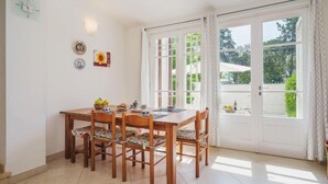 A dining area with a wooden table and chairs, a clock on the wall, and a view through the glass doors. - Villa Clara by Interhome (Lido di Camaiore)