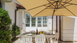 An outdoor dining area with a table set for two, a yellow umbrella, and a bottle of wine. - Villa Clara by Interhome (Lido di Camaiore)