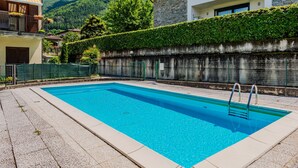 A rectangular swimming pool with a ladder, surrounded by a pebble-lined deck. - La Perla by Interhome (Colico)