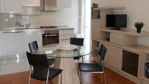 Een moderne keuken met witte kasten, een glazen eettafel en zwarte stoelen.