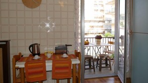 Une petite cuisine avec une horloge, une table et des chaises, et une vue sur le balcon extérieur.