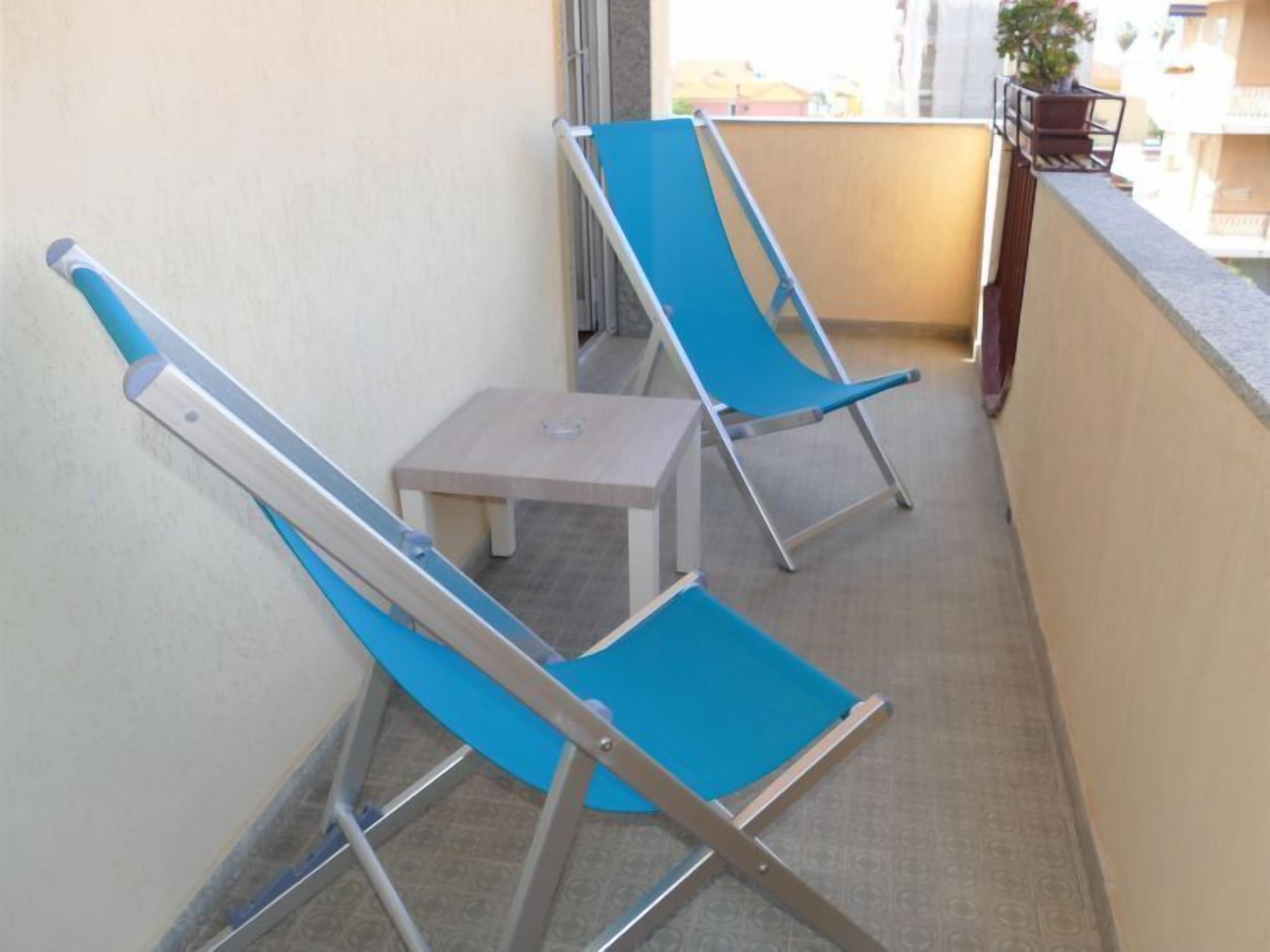 Een balkon met twee blauwe loungestoelen en een klein tafeltje.