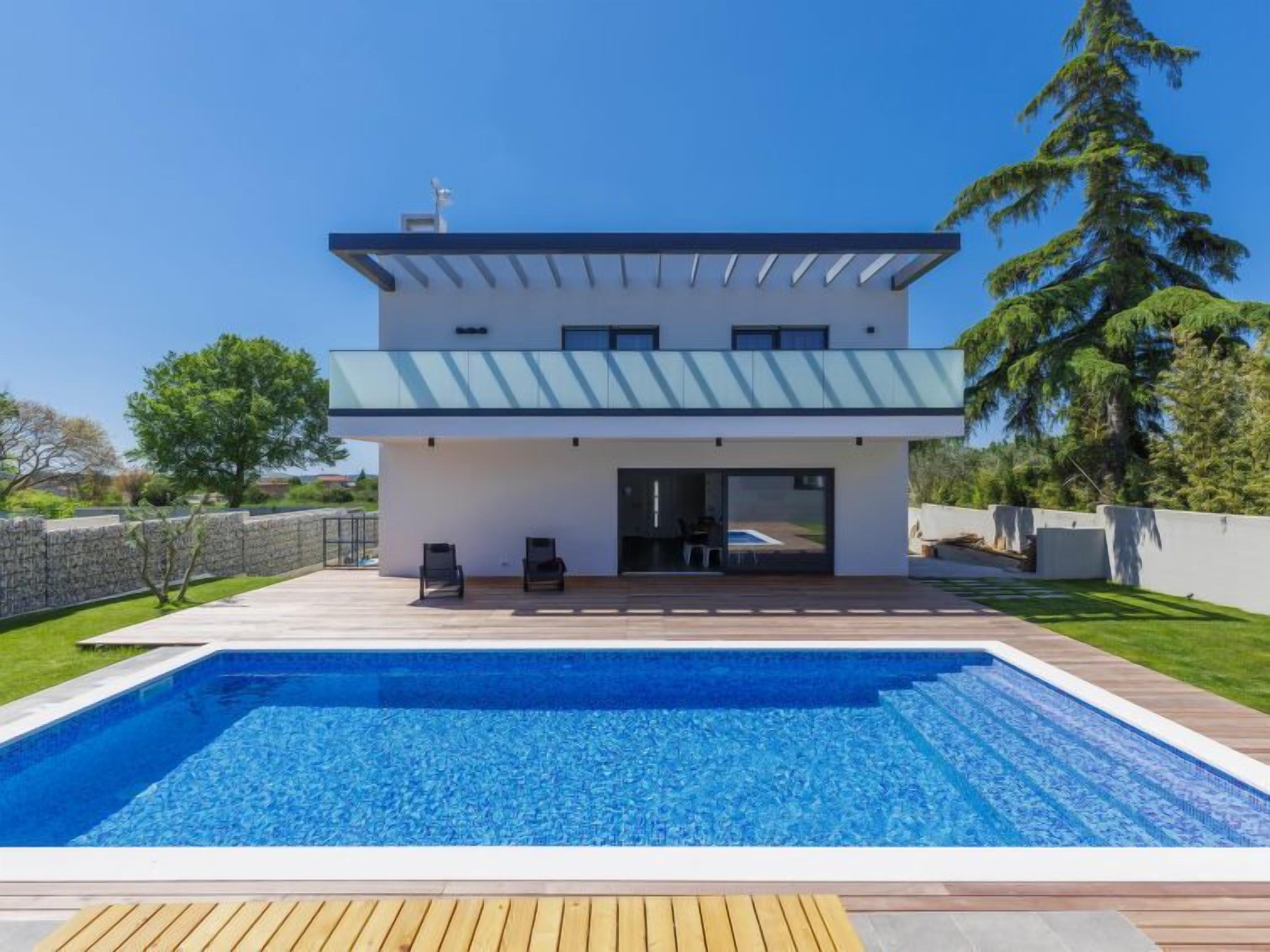 A modern two-story house with a swimming pool in the front.