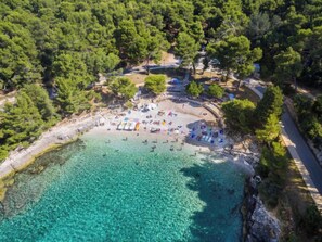 An aerial view of a beach with clear turquoise water, surrounded by dense green trees. - Villa Dora by Interhome (Pula)