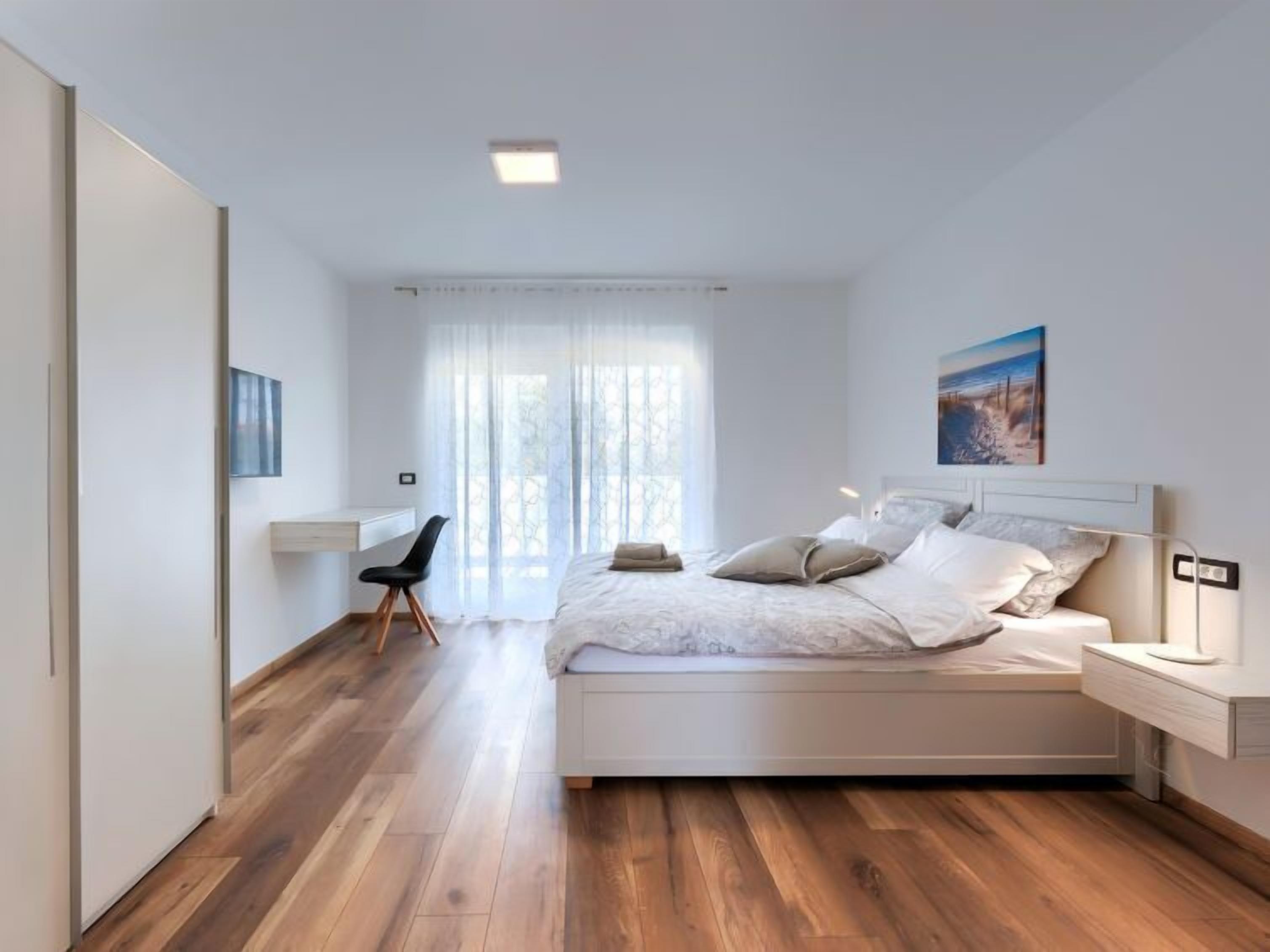 Quarto moderno com uma cama grande, uma escrivaninha e uma cadeira.