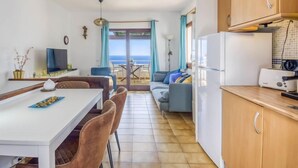 A compact living space with a dining area, kitchen, and a balcony with a view. - Vacation home Bramer by Interhome (Roses)