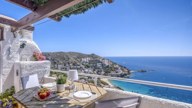 A terrace with a table set for two, overlooking a coastal town and the sea. - Vacation home Bramer by Interhome (Roses)