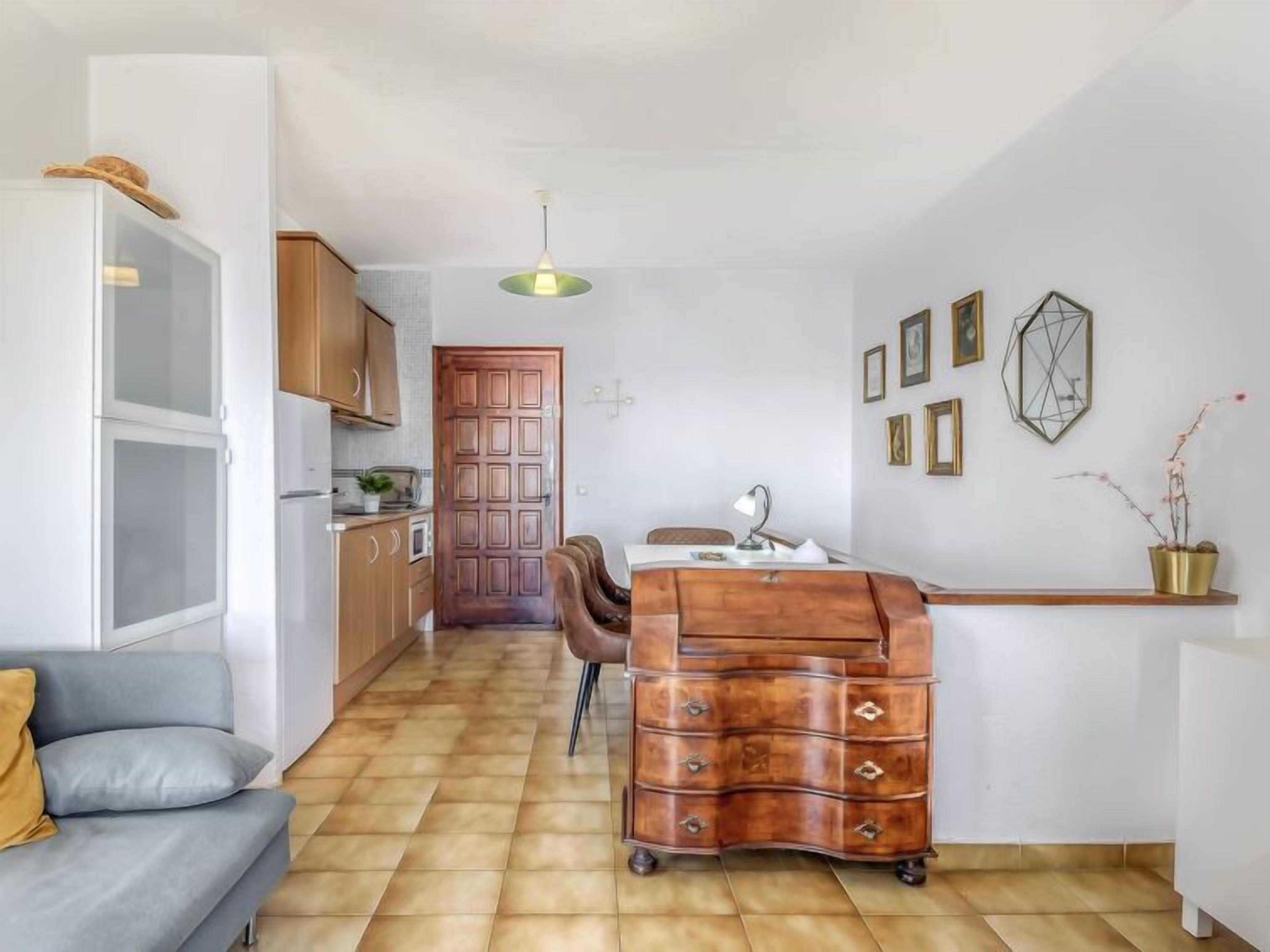 Un espacio habitable compacto con kitchenette, comedor y sofá.