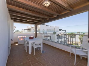 A balcony with a white table and chairs, a view of the sea, and a tiled floor. - Punta Candor - Seaview by Interhome (Rota)