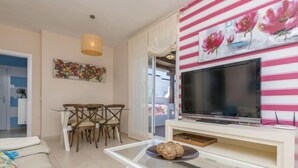 Un salon moderne avec un téléviseur, un coin repas et un canapé.