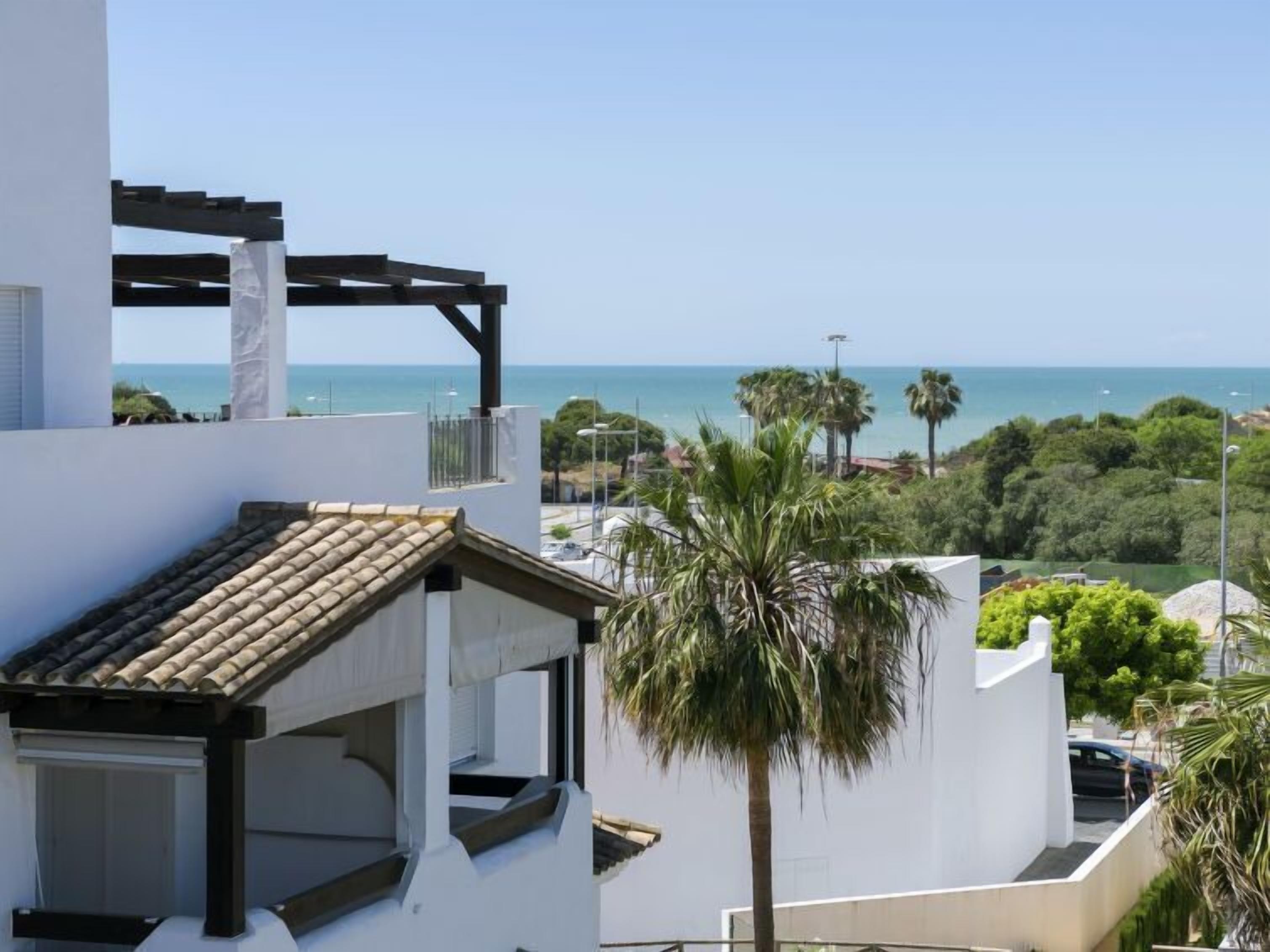 Een modern gebouw met een terras met uitzicht op de kust, met een pergola en uitzicht op zee.