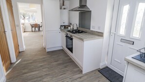 Una cocina moderna con muebles blancos, estufa a gas y campana extractora de acero inoxidable.