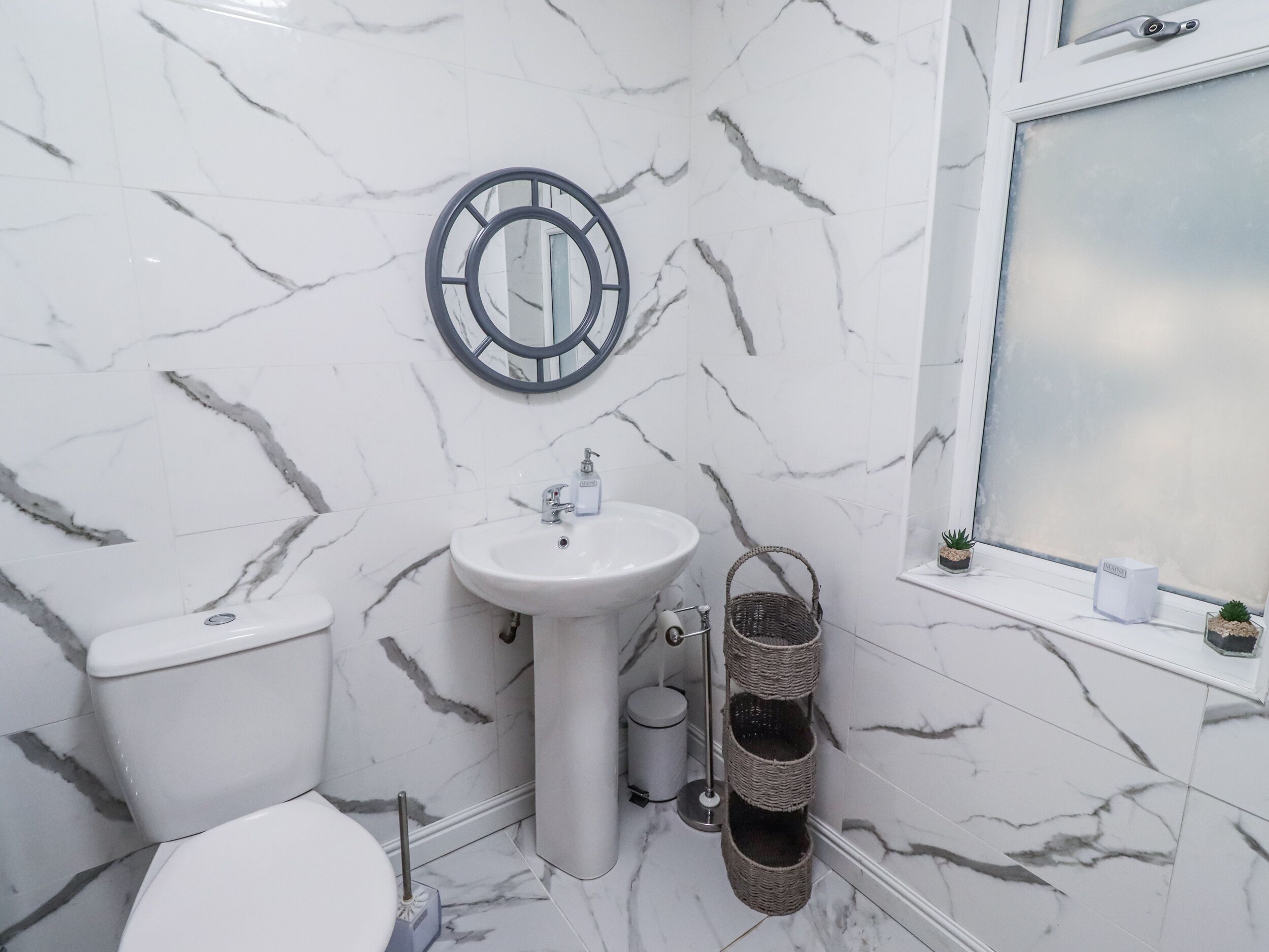 A bathroom with a toilet, sink, and mirror.
