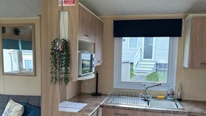 Une petite cuisine équipée d’un four à micro-ondes, d’un évier et de placards. Un panneau « Il est interdit de fumer » est visible sur le mur.