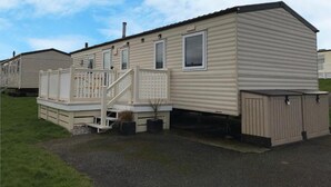 Une maison mobile dotée d’une véranda, d’une petite terrasse et d’un garage.