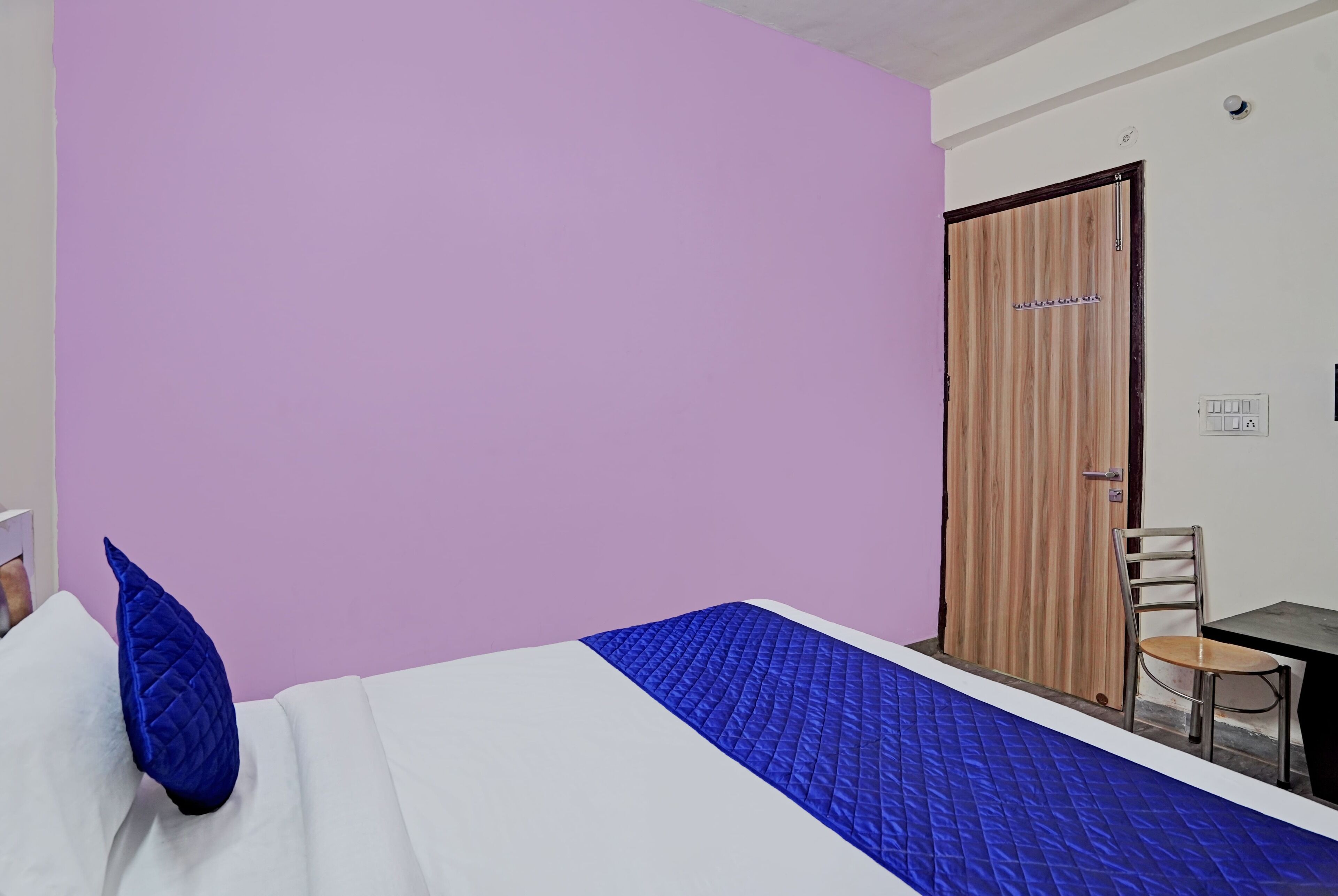A room with a bed, a chair, and a wooden door.