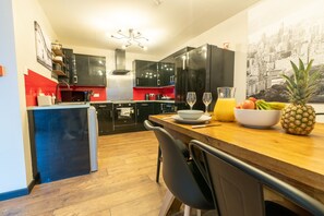 Une cuisine moderne avec des meubles noirs, un plan de travail en bois et un coin repas avec une chaise.