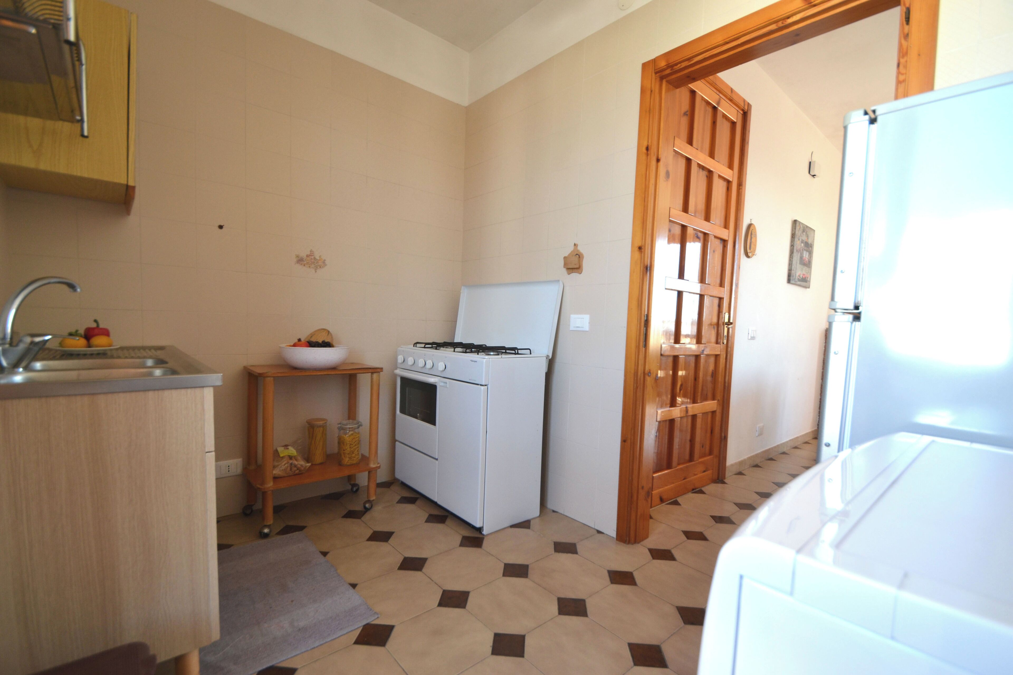 A compact kitchen with a gas stove, sink, and a wooden door leading to another room.