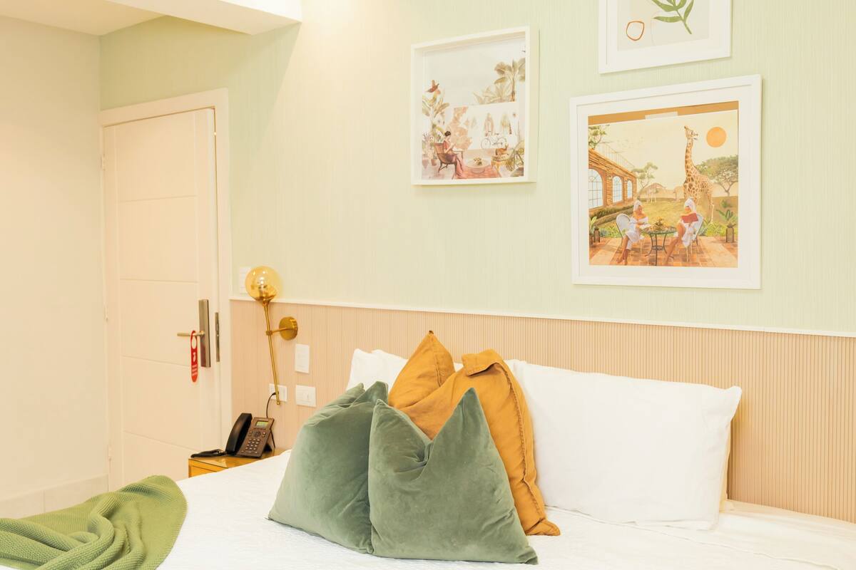 A neatly made bed with pillows, a bedside lamp, and framed pictures on the wall.