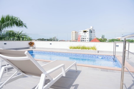 Una piscina al aire libre, sombrillas, sillones reclinables de piscina