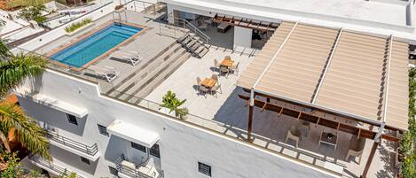 A rooftop with a swimming pool, outdoor seating, and a pergola.