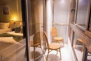 Una habitación de hotel con una cama, dos sillones de mimbre, una mesita y una mesita de noche.